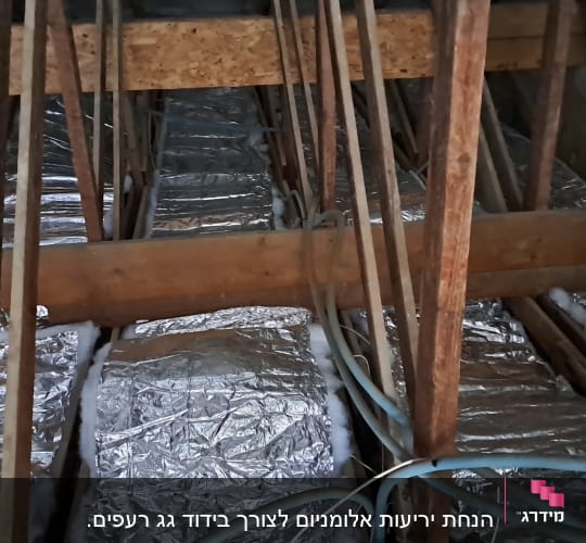 קורות עץ וגגות מבודדים בנייר כסף בעליית גג